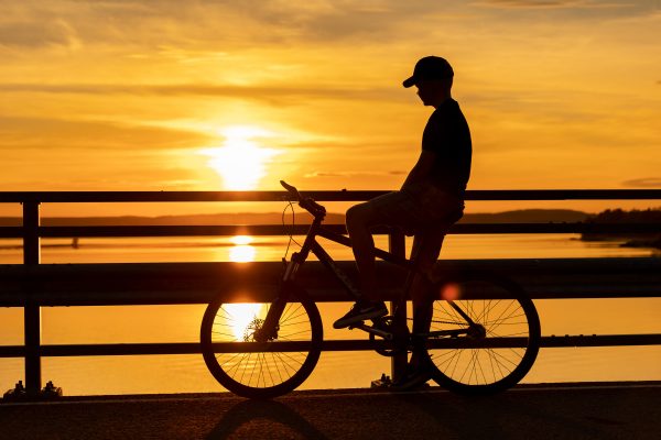Poika ja pyörä auringonlaskussa