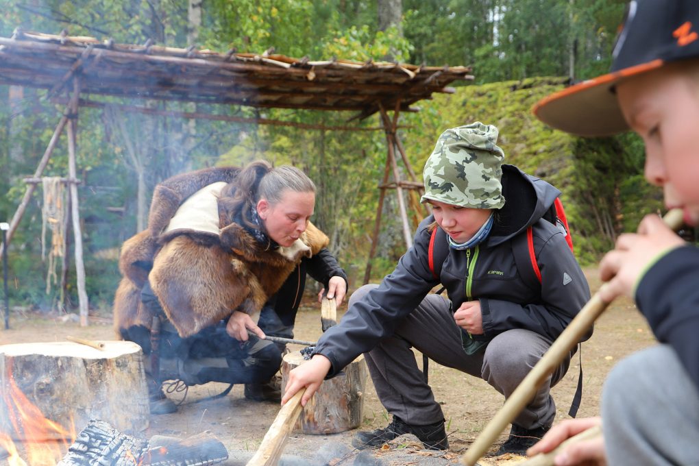 Kivikauden kylän opas Marlene Lindeman opettaa lapsille tulentekomenetelmiä esihistoriallisin menetelmin. Kuva: SM / JT.