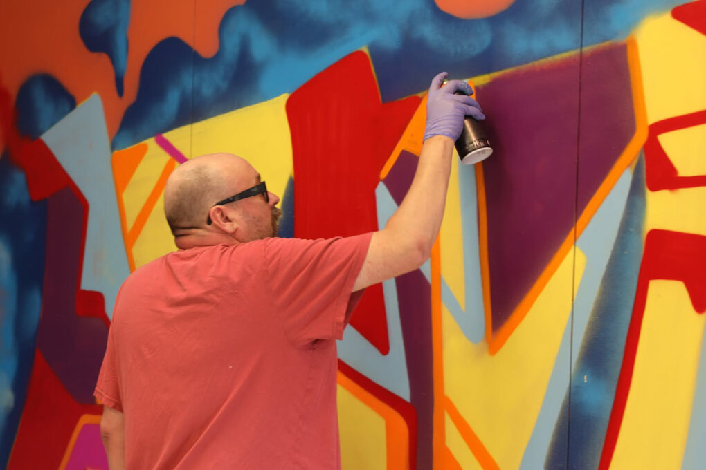 Pekka Karppinen maalaa graffitia Galleria Ahkun punaisessa huoneessa. Kuva: Ahku / JT.