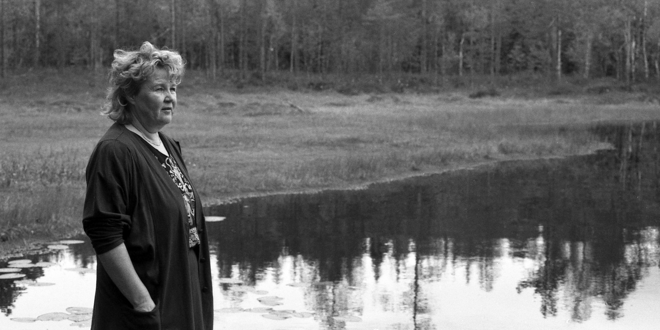 Tekstiili- ja kuvataiteilija Saara Pylvänäinen lammen rannalla Saarijärvellä. Kuva: Sampo-lehti, Saarijärven museon kuva-arkisto.